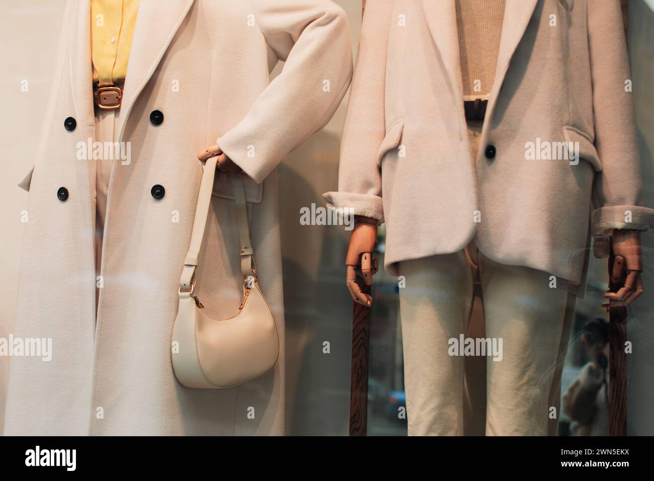 Schicke Schaufensterpuppen in einem Schaufenster, gekleidet mit saisonalem Modetuch. Weißer Mantel, Jacke und Handtasche Stockfoto
