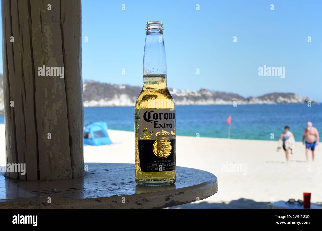 Eine Flasche Corona Extra Bier steht auf einem Tisch am Strand in Huatulco, Oaxaca, Mexiko. Im Ausland leben Stockfoto