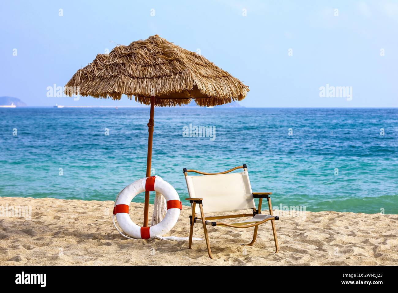 Tropischer Sandstrand, Blick auf den Sonnenschirm, Rettungsring und Sessel im Seebad. Hintergrund für Urlaub und Reisen Stockfoto