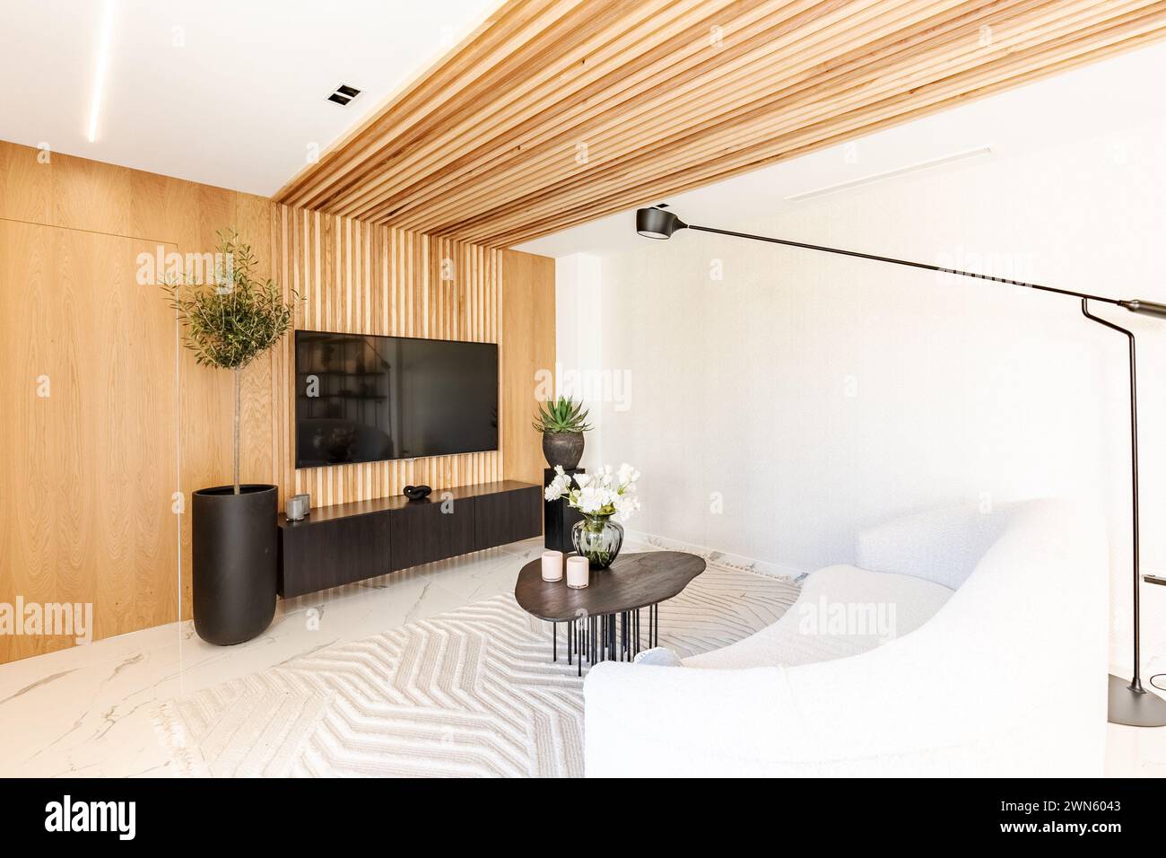 Ein Bild von einem Sofa und Couchtisch vor einem großen Fernseher an einer Holzwand Stockfoto
