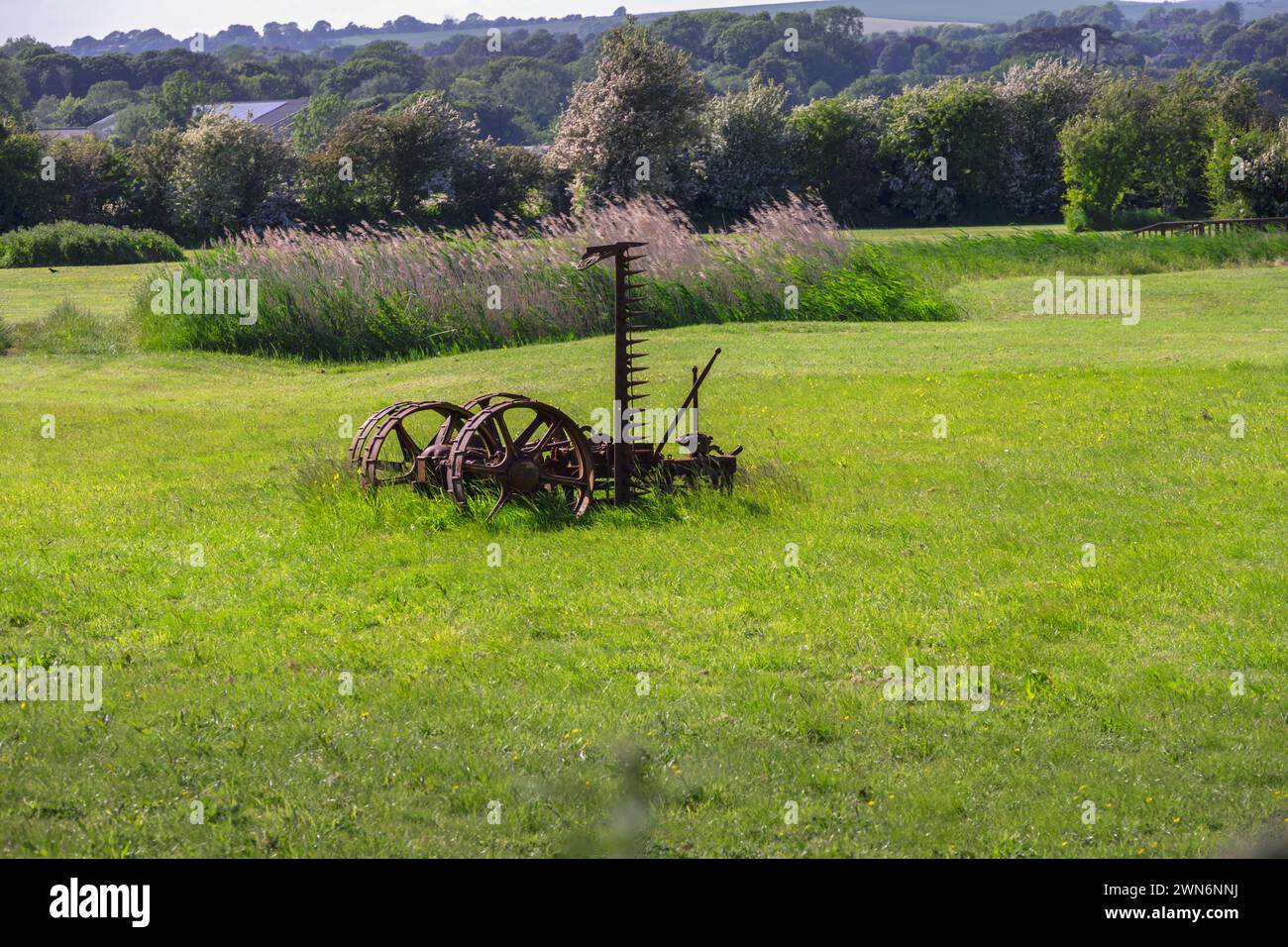 Alte, rostige Landmaschinen auf einem Feld im Frühjahr, East Sussex, England Stockfoto