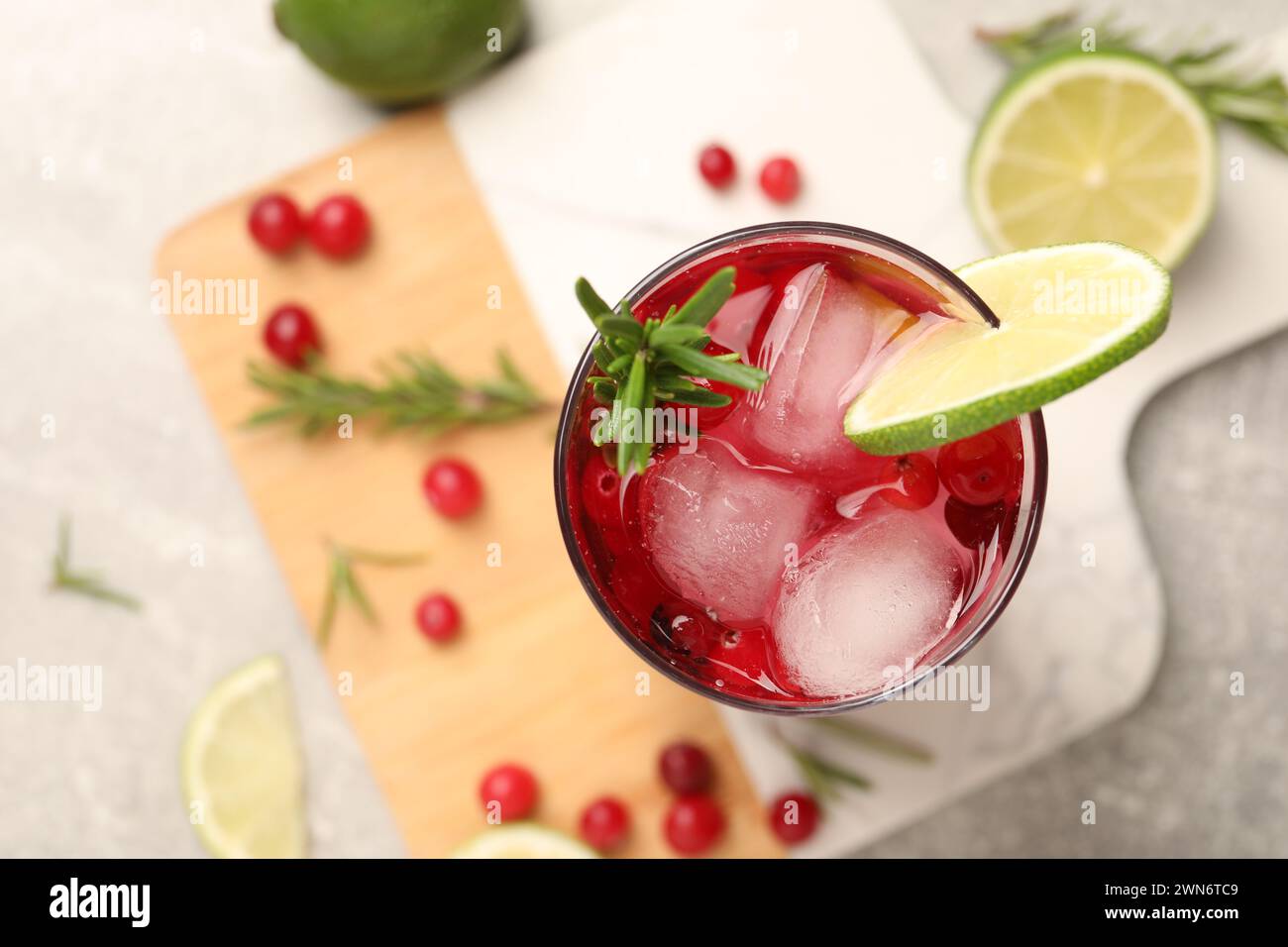 Leckerer Cranberry-Cocktail mit Rosmarin und Limette im Glas auf dem Tisch, Blick von oben Stockfoto