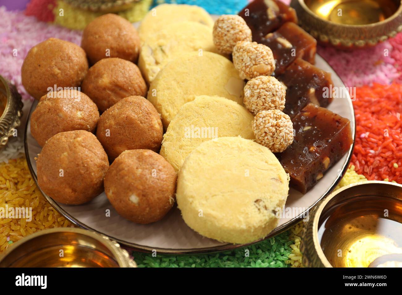 Diwali-Feier. Leckere indische Süßigkeiten, Diya-Lampen und bunte Rangoli auf dem Tisch, Nahaufnahme Stockfoto