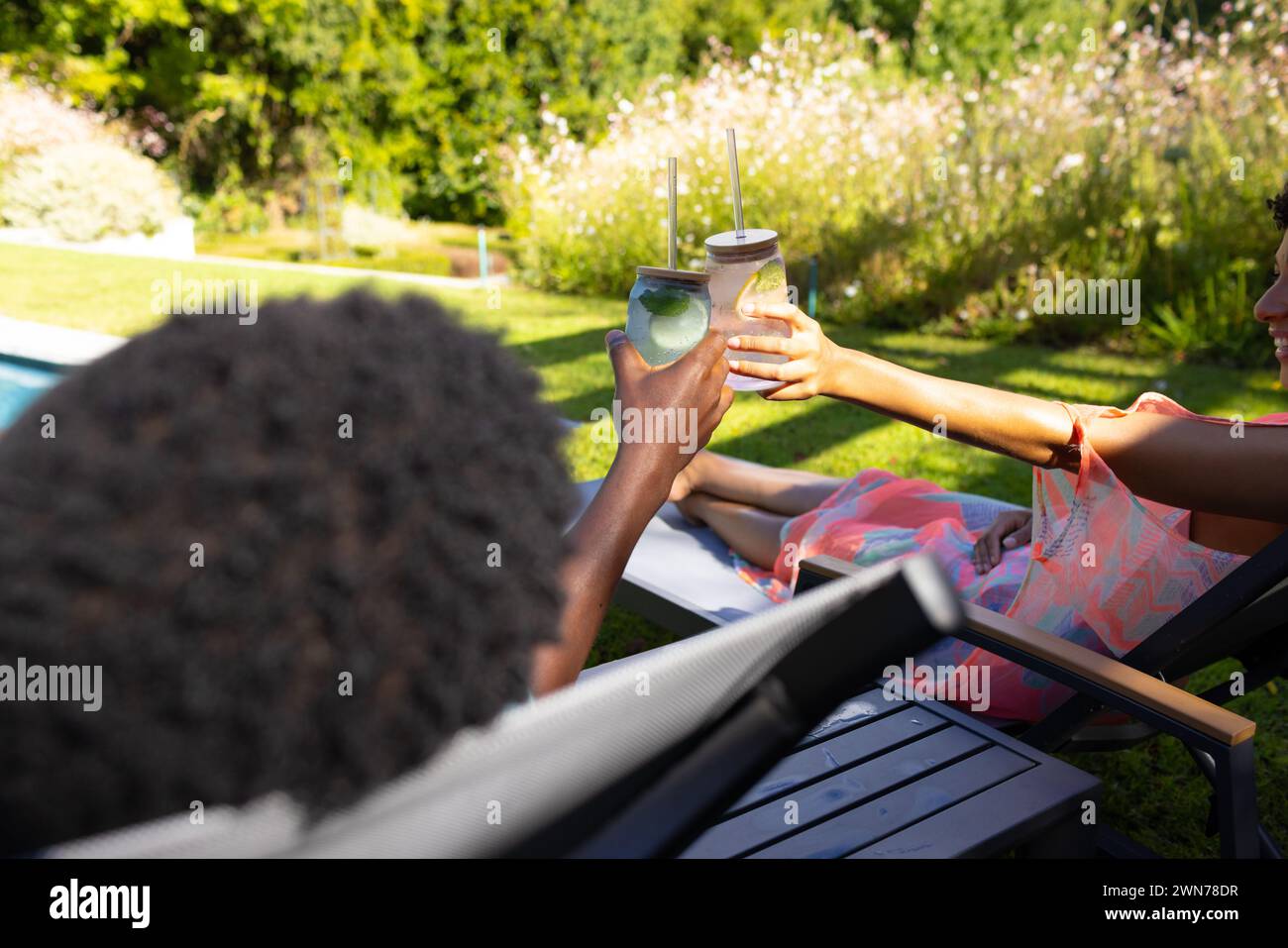 Birassisches afroamerikanisches Paar klitzt in einem sonnigen Garten zu Hause auf Gläser Stockfoto