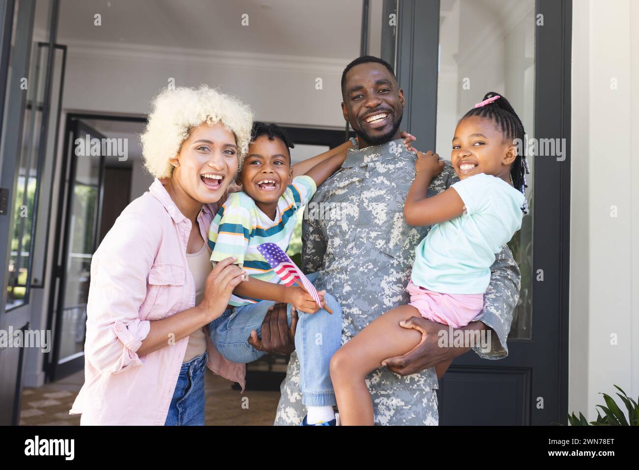 Afroamerikanischer Soldat in Militäruniform mit seiner Familie vor ihrem Haus Stockfoto