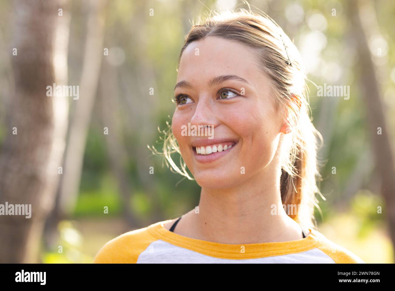 Eine junge kaukasische Frau lächelt sanft und blickt auf einer Wanderung von der Kamera weg Stockfoto