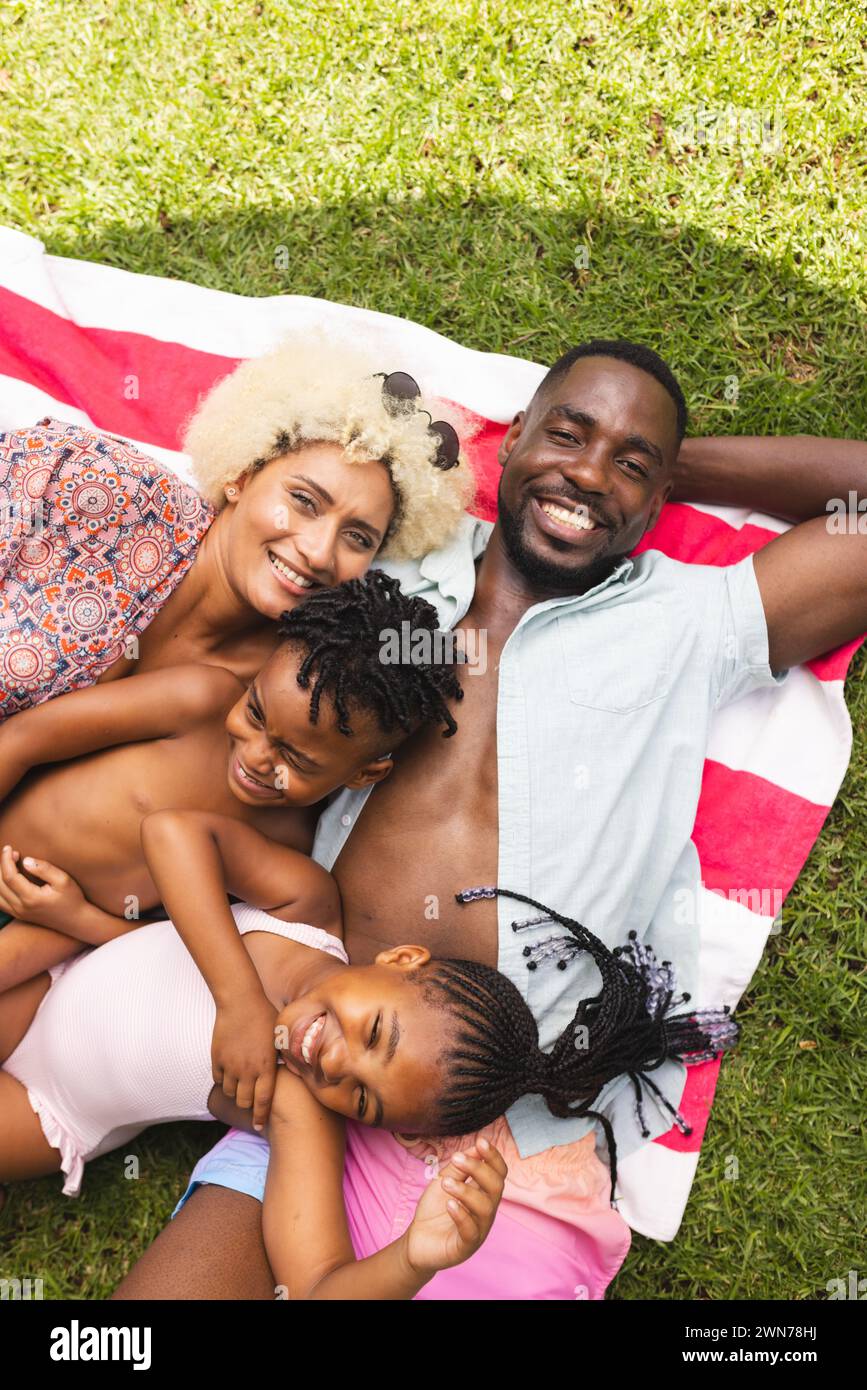 Die afroamerikanische Familie genießt einen sonnigen Tag im Freien und liegt auf einer gestreiften Decke Stockfoto