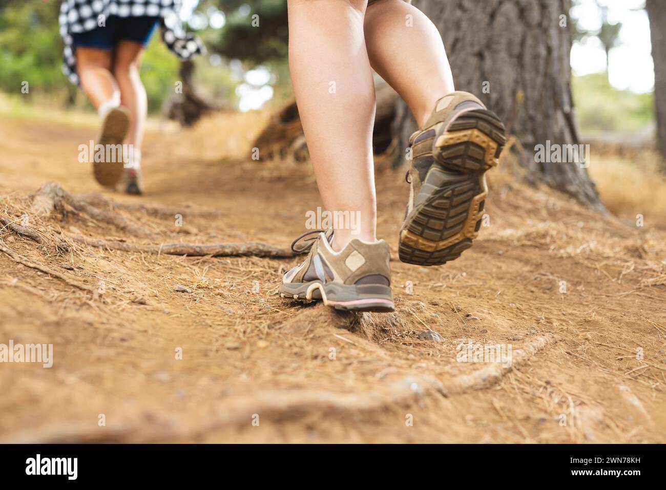 Nahaufnahme von Wanderschuhen auf einem Feldweg, mit einem weiteren Wanderer auf einer Wanderung Stockfoto