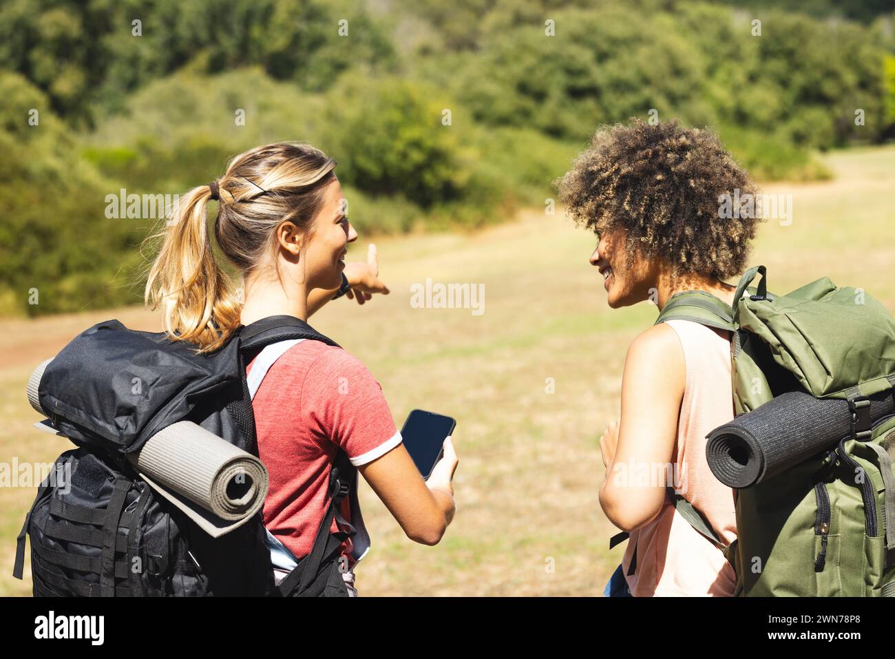 Zwei Frauen mit Rucksäcken unterhalten sich draußen auf einer Wanderung Stockfoto