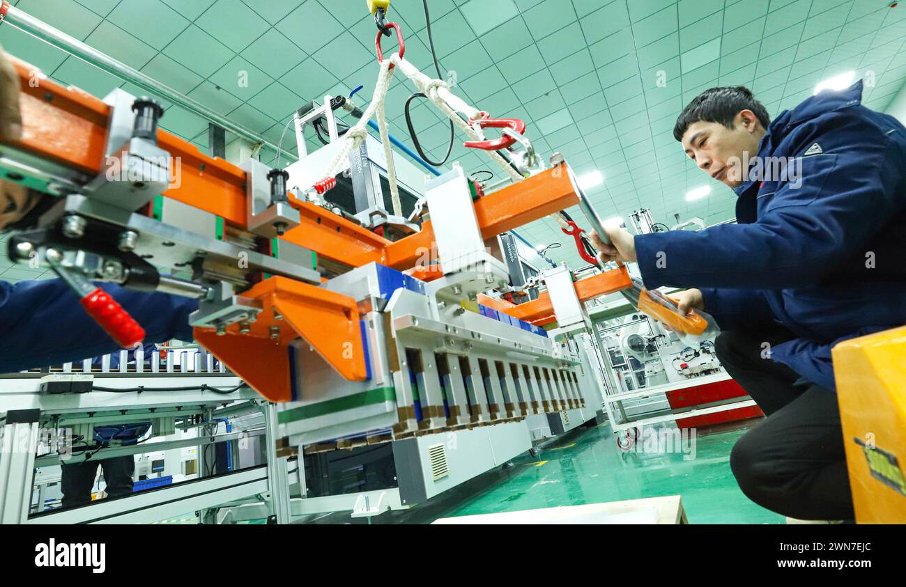 ZHANGYE, CHINA – 29. FEBRUAR 2024 – Arbeiter heben Module an einer automatisierten Produktionslinie für Energiespeicheranlagen an, die Module in herstellen Stockfoto