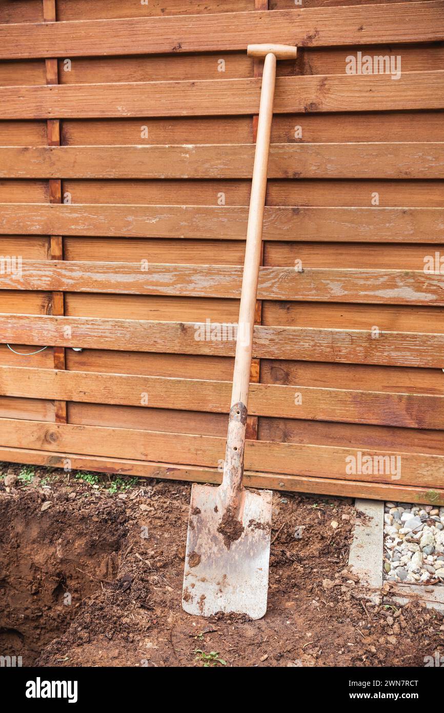 Spaten in einem Garten mit Erde und hölzernem Gartenzaun Stockfoto