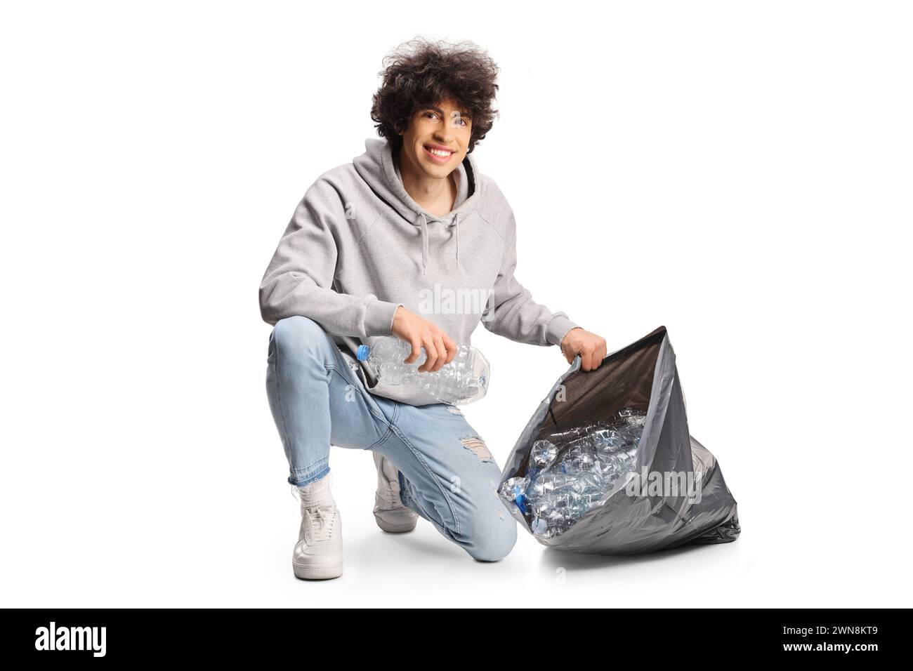 Junger Mann sammelt Plastikflaschen und lächelt in die Kamera, isoliert auf weißem Hintergrund Stockfoto