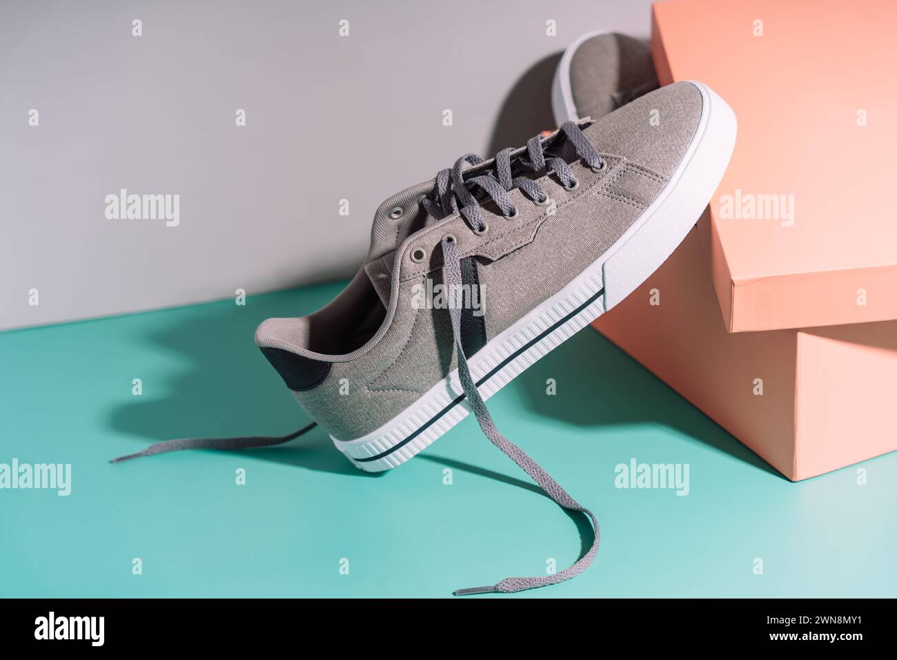 Graue Sneakers aus Stoff mit weißen Gummisohlen vor der Box Stockfoto