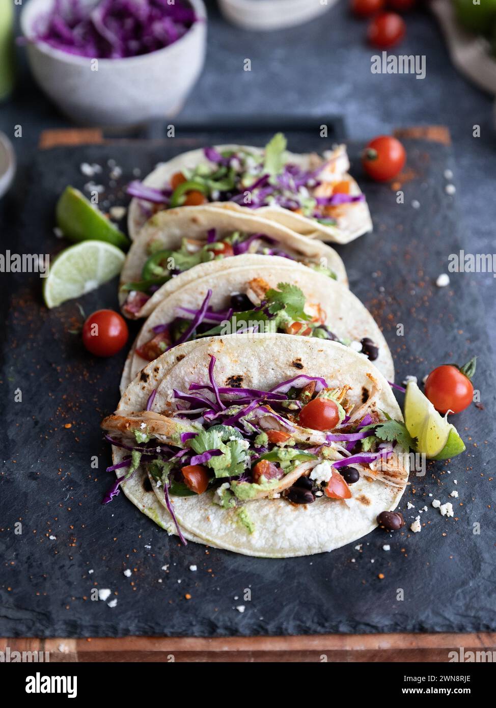 Gestapelte Tacos mit bunten Zutaten auf dunklem Hintergrund Stockfoto
