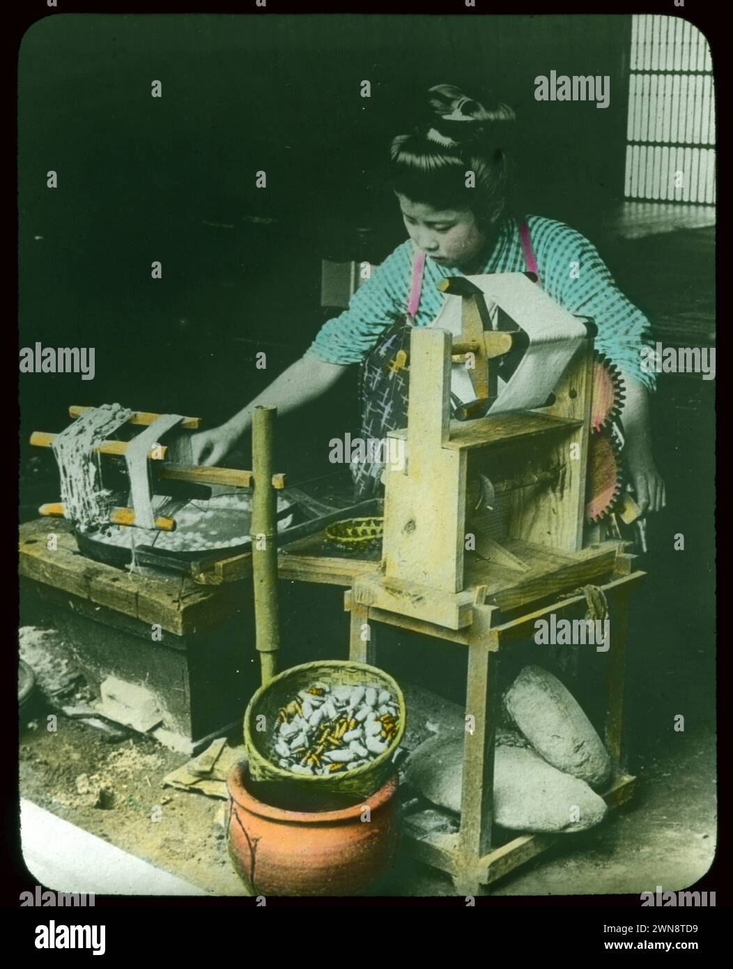 Japaner arbeiten Seide aus Kokkons in rustikale Ausrüstung. Aus Hebert Geddes 'Life in Japan' Kollektion: Handfarbige Vintage-Glasfolien aus der Meiji-Ära. Yokohama, Japan Ende des 19. Jahrhunderts. Diese Bilder von verschiedenen japanischen Künstlern wurden an Besucher verkauft. Stockfoto