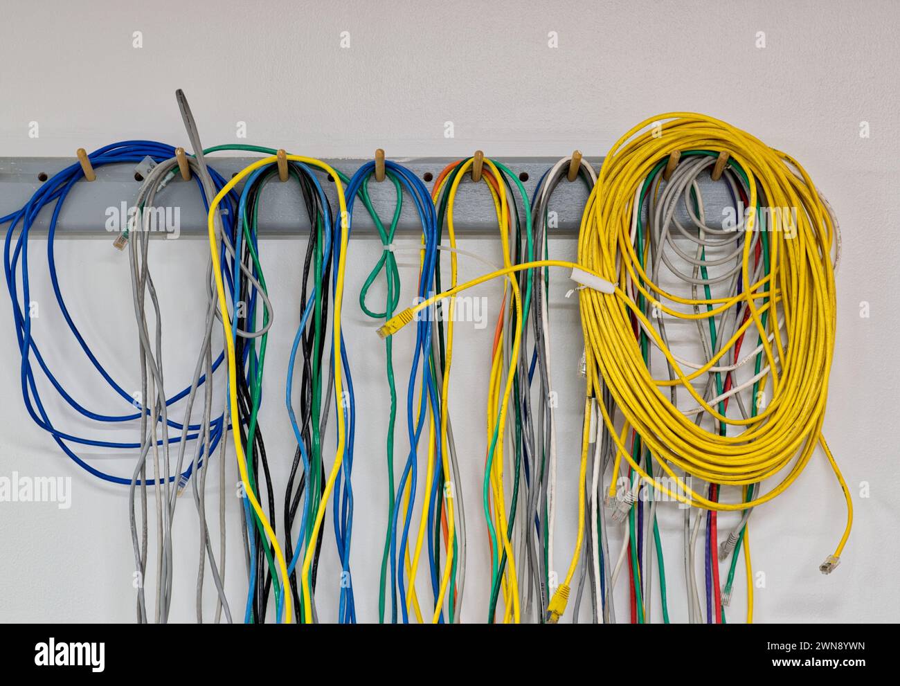 Bunte alte elektrische Kabel hängen an einer Wand. CAT5 Twisted-Pair-Kabel für Computernetzwerke. Stockfoto
