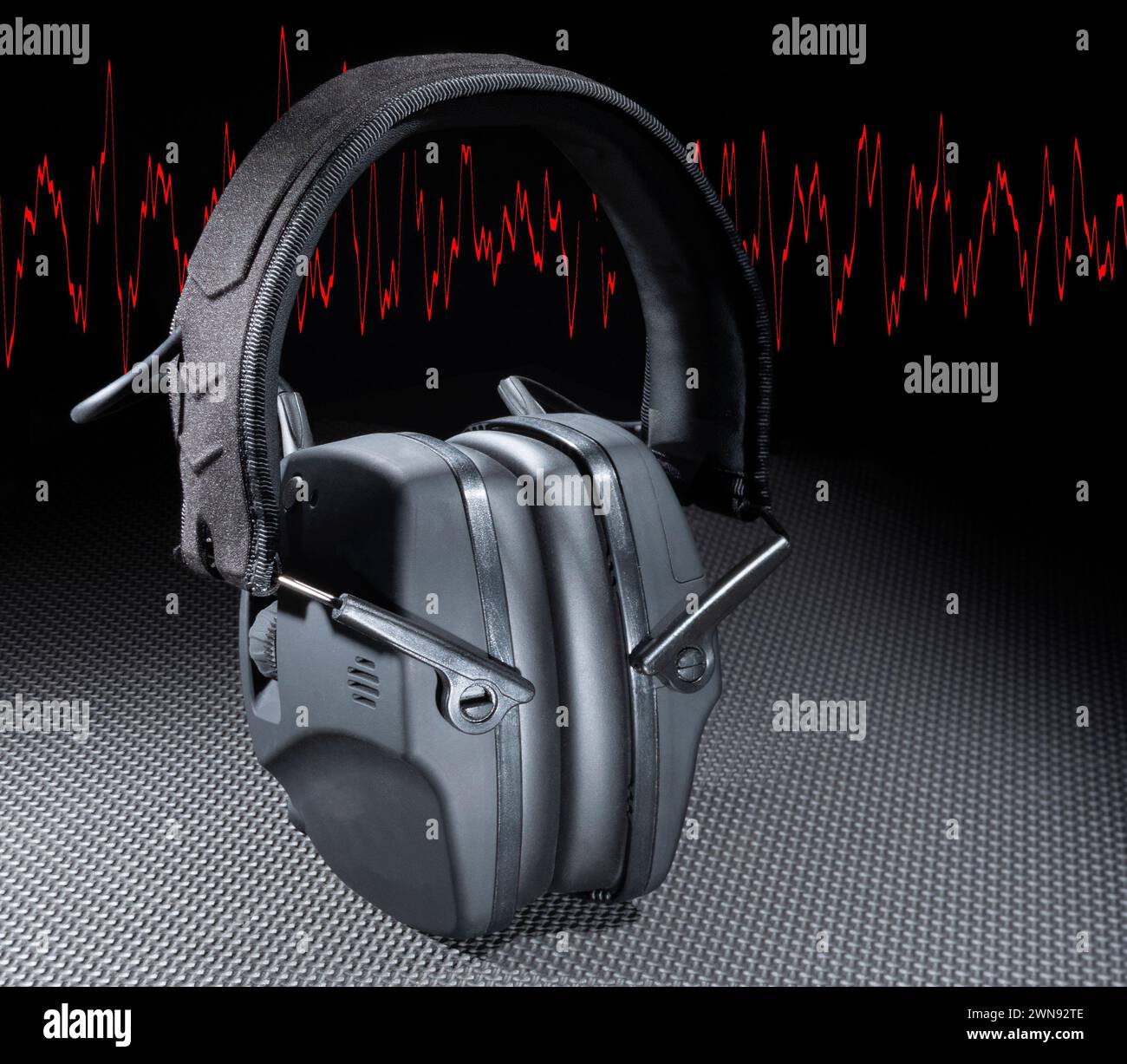Elektronisches Gehörschutz-Headset mit roter Sinuswelle im Hintergrund Stockfoto