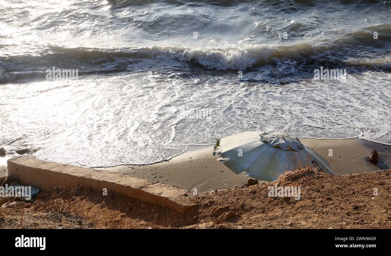 Sonnenschirm am Strand mit Flut kommt in Vouliagmeni Athen Griechenland Stockfoto