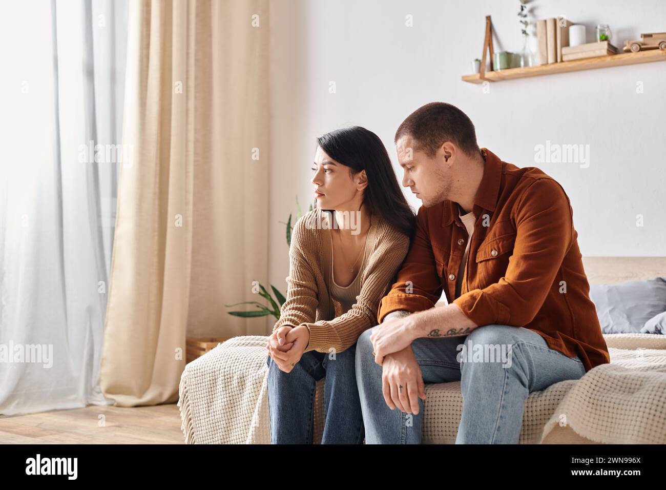 Junge frustrierte multiethnische Paare sitzen und sprechen zu Hause auf dem Bett, Beziehungsschwierigkeiten Stockfoto