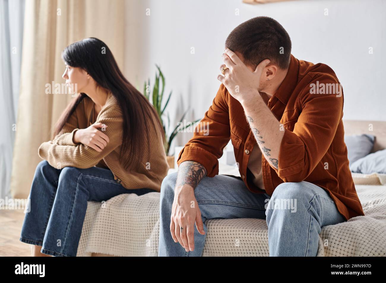 Verärgertes junges interrassisches Paar, das zu Hause im Schlafzimmer sitzt, Beziehungsschwierigkeiten Konzept Stockfoto