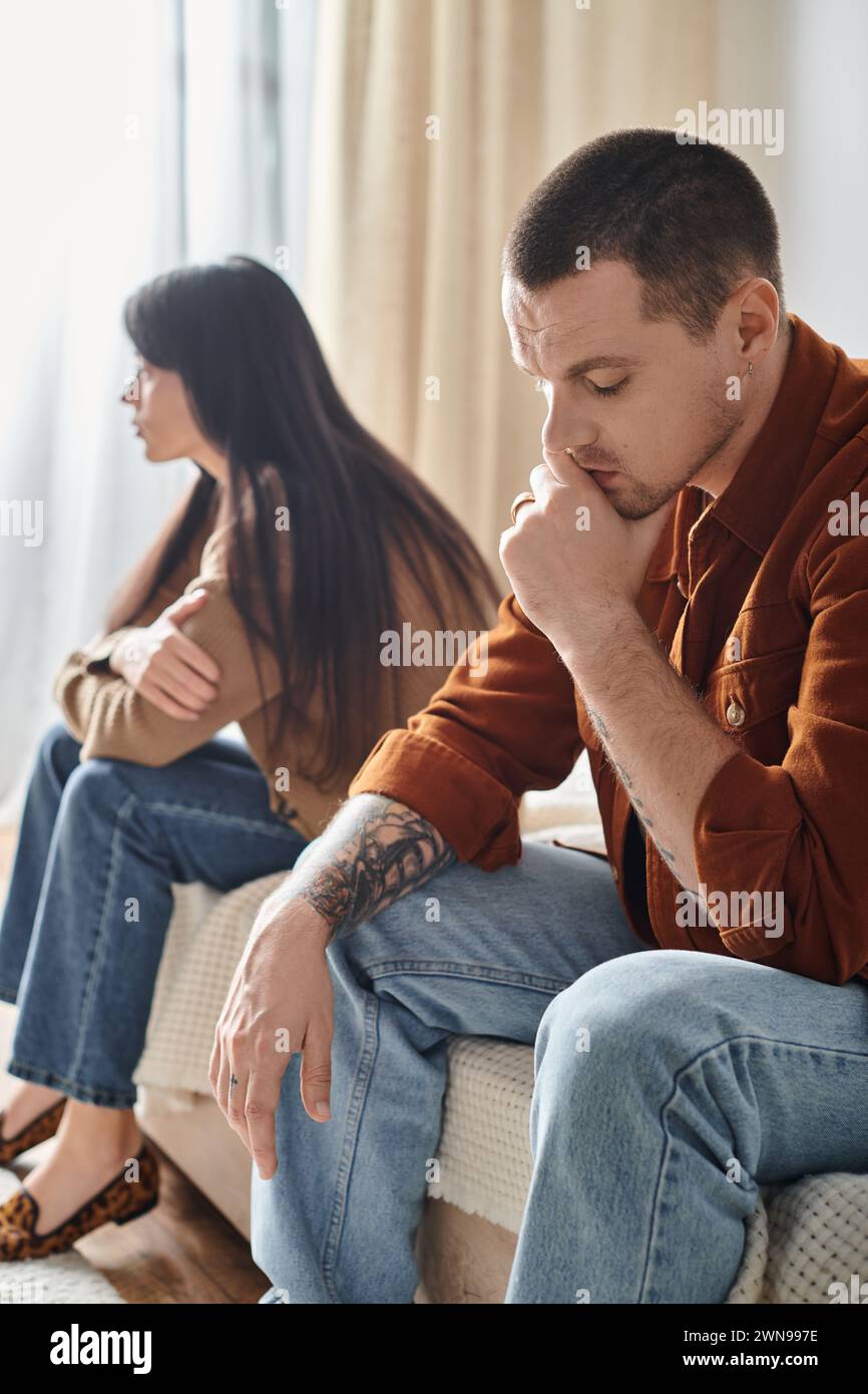 Trauriges und junges interrassisches Paar, das zu Hause im Schlafzimmer sitzt, Beziehungsschwierigkeiten Konzept Stockfoto