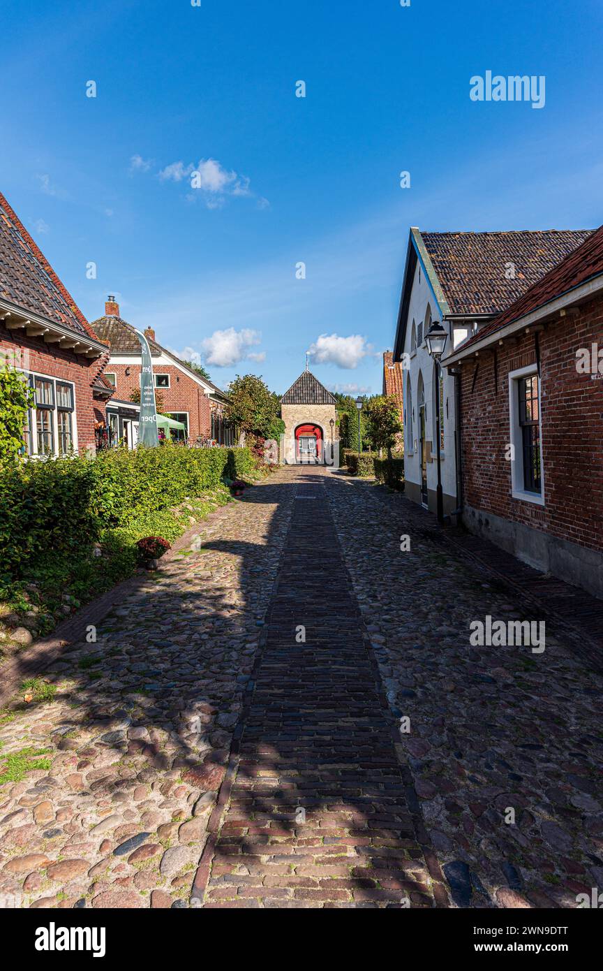 Historische Dorfstraße mit Kopfsteinpflaster und Hausfassaden im Sonnenlicht, Bourtange Festung, Groningen, Niederlande Stockfoto