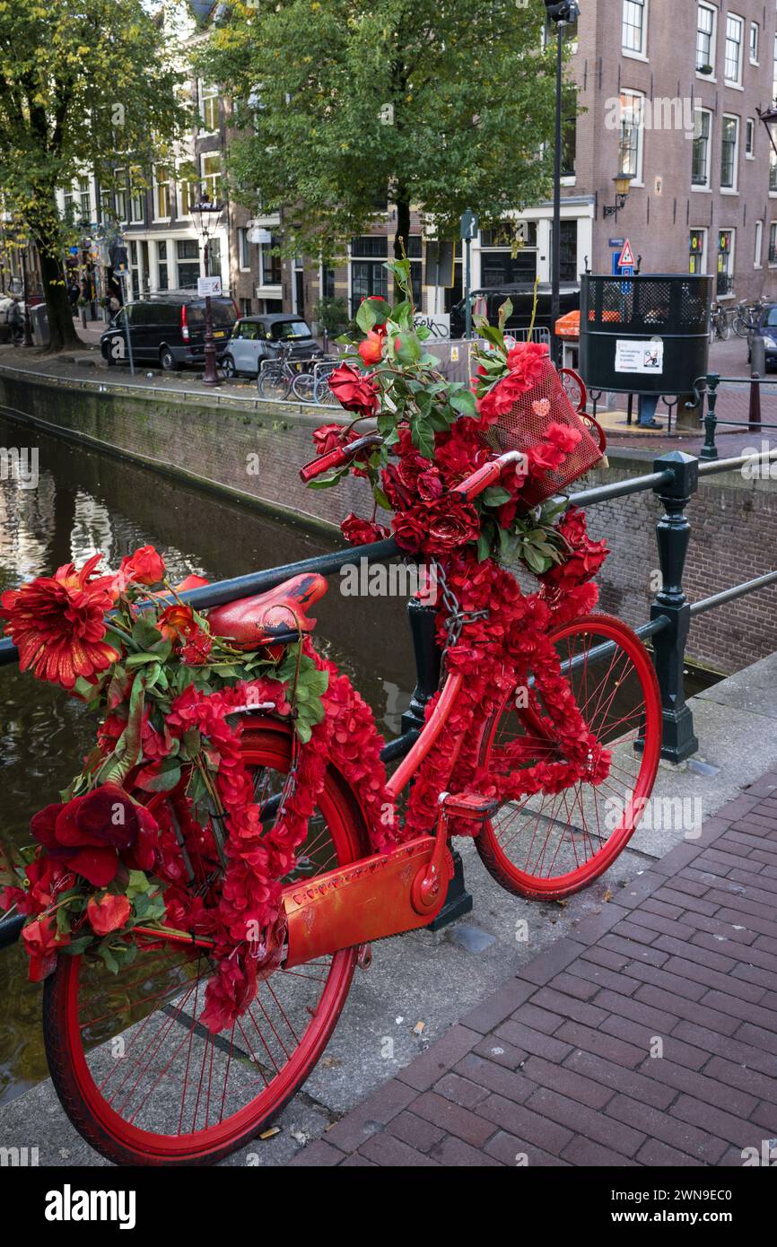 Ikonisches rot lackiertes Fahrrad auf dem im Rotlichtviertel von Amsterdam, Niederlande Stockfoto