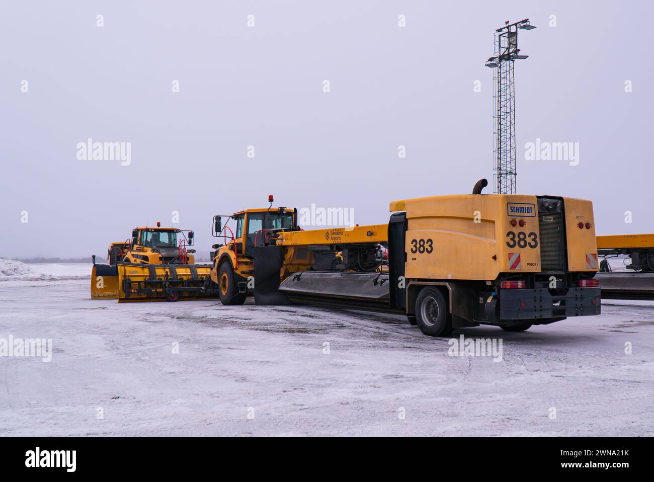 Eine Pflug-, Kehrer- und Blasmaschine (Schneepflug) am Flughafen Umeå, Swedavia Flughäfen, gelb, von Schmidt aus, wartet auf einen bevorstehenden Schneefall. Stockfoto