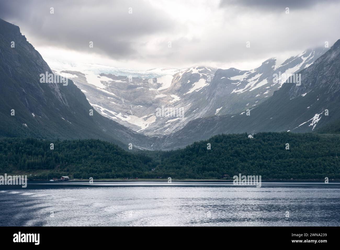 Der Svartisen-Gletscher, umgeben von üppigen grünen Hängen und einem spiegelähnlichen Fjord, in einer ruhigen Schaustellung der natürlichen Schönheit Norwegens Stockfoto