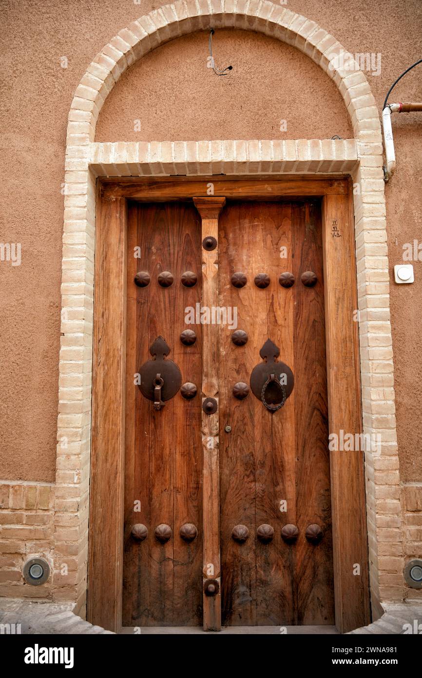 Alte Holztür eines Hauses mit zwei separaten Klopfern - Metallstange für Männer und Metallring für Frauen. Yazd, Iran. Stockfoto
