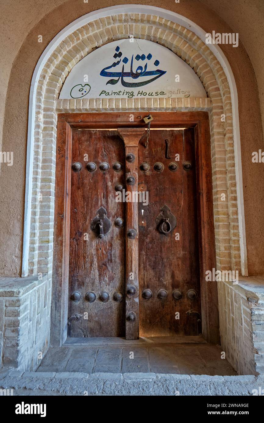 Alte Holztür mit zwei separaten Klopfern - Metallstange für Männer und Metallring für Frauen. Yazd, Iran. Stockfoto