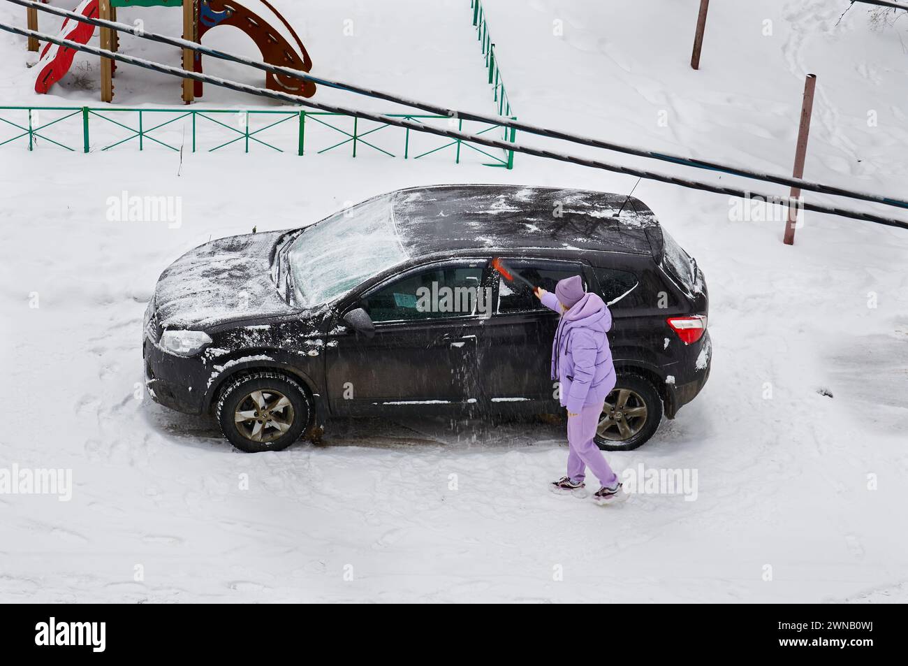 5. Dezember 2021 Russland, Region Twer, Stadt Rzhev, ein Mädchen reinigt ihr Auto vom Schnee. Wintermorgen. Stockfoto