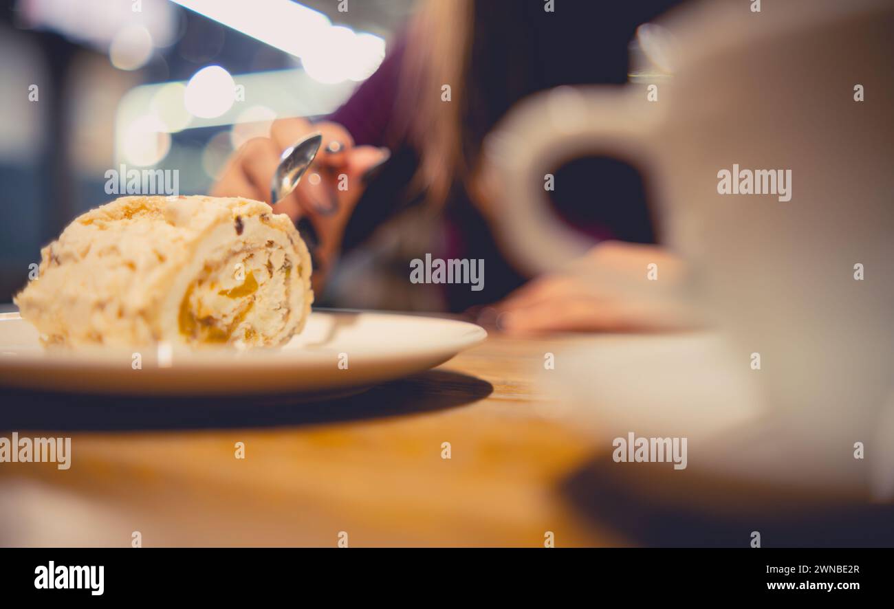 Genießen Sie einen dekadenten Creme Cake in einem gemütlichen Evening Cafe, mit einer Gabel, um einen zarten Happen zu nehmen Stockfoto