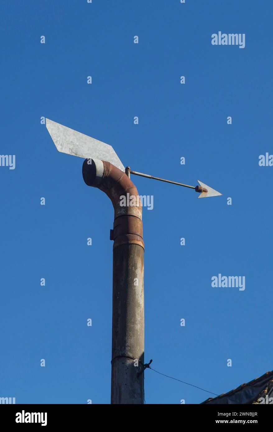 Kaminkappe mit Pfeil für den Inlandswind. Blauer Himmel Hintergrund Stockfoto