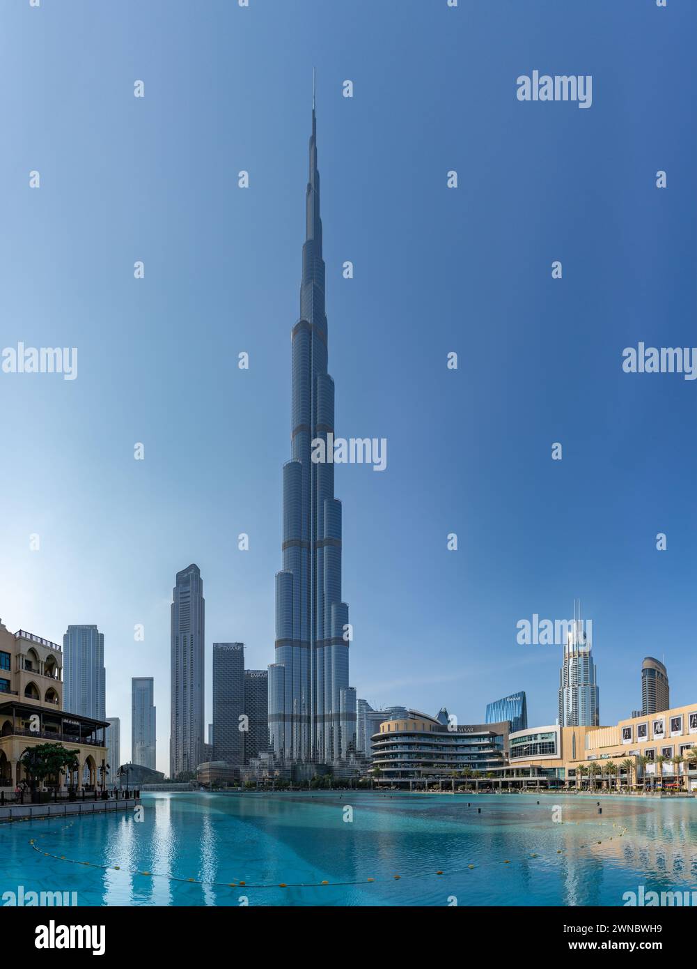 Ein Bild des Burj Khalifa, der die nahe gelegenen Gebäude in der Innenstadt von Dubai und das blaue Wasser des Burj Khalifa Lake überragt. Stockfoto
