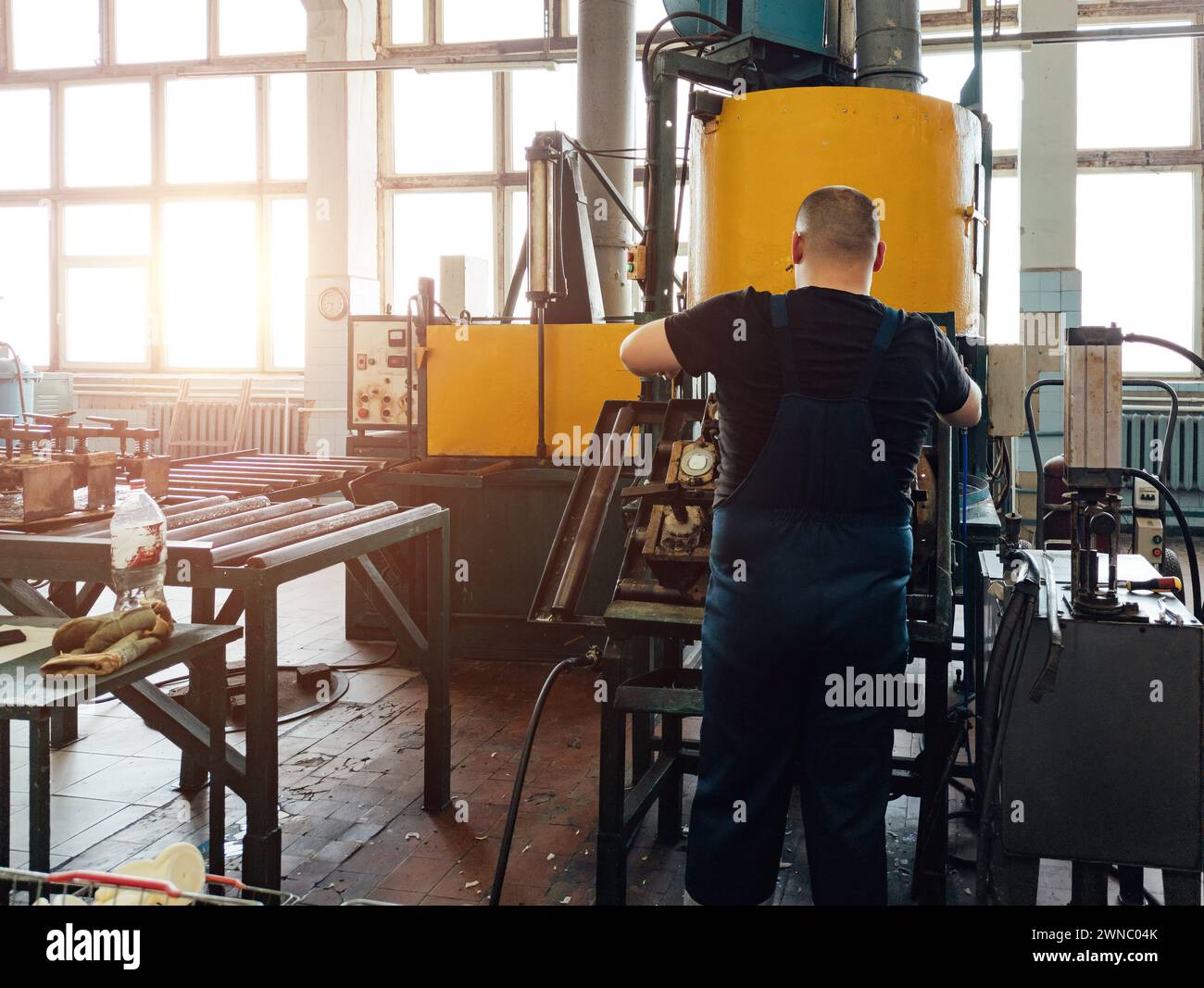 Der Arbeiter bedient die Stanzformmaschine aus Kunststoff in der Werkstatt. Stockfoto