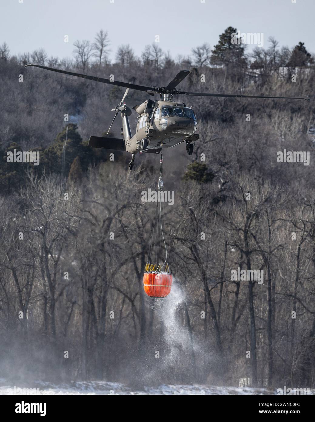 Ein Hubschrauber der North Dakota National Guard UH-60 Black Hawk transportiert 660 Liter Wasser in einem Bambi Eimer, um am 29. Februar 2024 auf einem Eisstau auf dem Missouri River in Bismarck, North Dakota, zu fallen, um das Eis aufzubrechen und Überschwemmungen zu verhindern. Über 70.000 Liter Wasser wurden in 4 Stunden fallen gelassen. (Foto der US-Nationalgarde von Staff Sgt. Samuel Kroll, North Dakota National Guard Public Affairs Office) Stockfoto