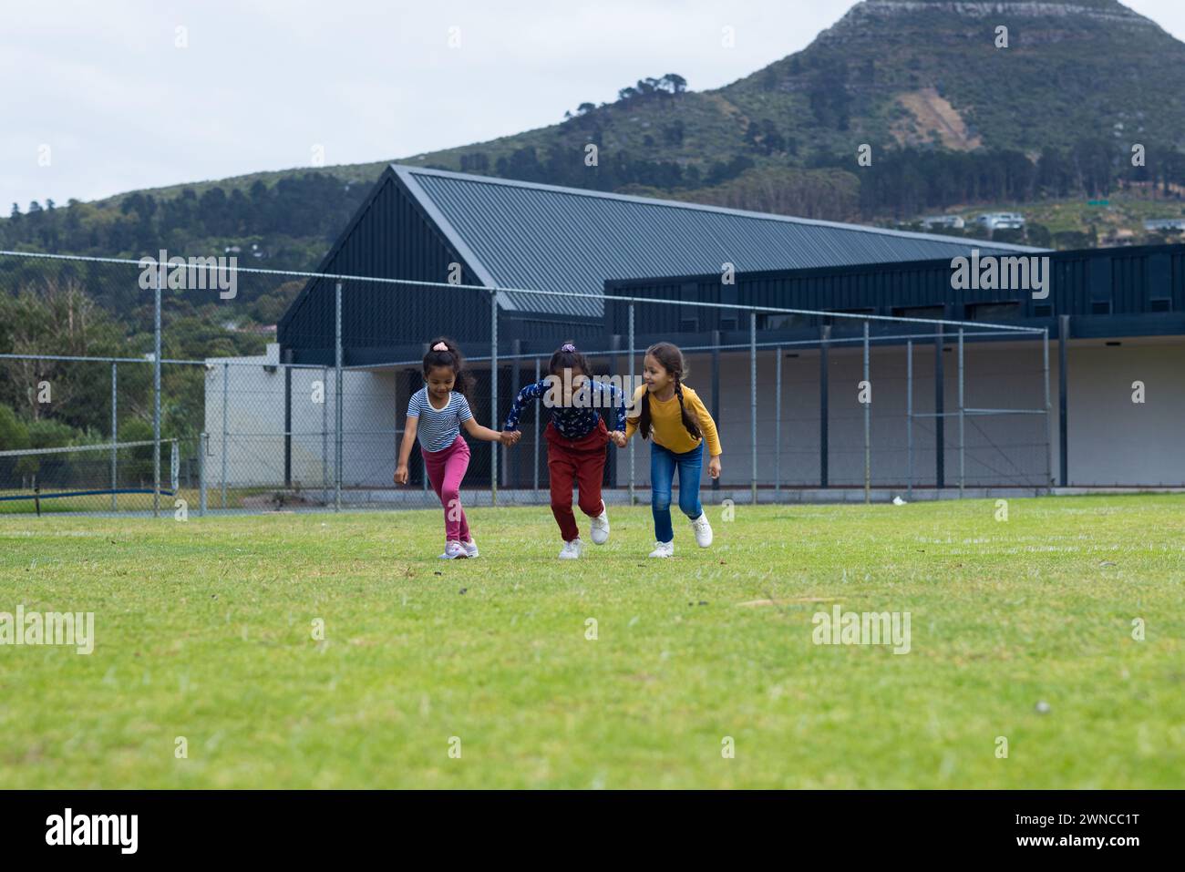 Drei rassistische Mädchen spielen auf einem Grasfeld in der Schule, mit Kopierraum Stockfoto
