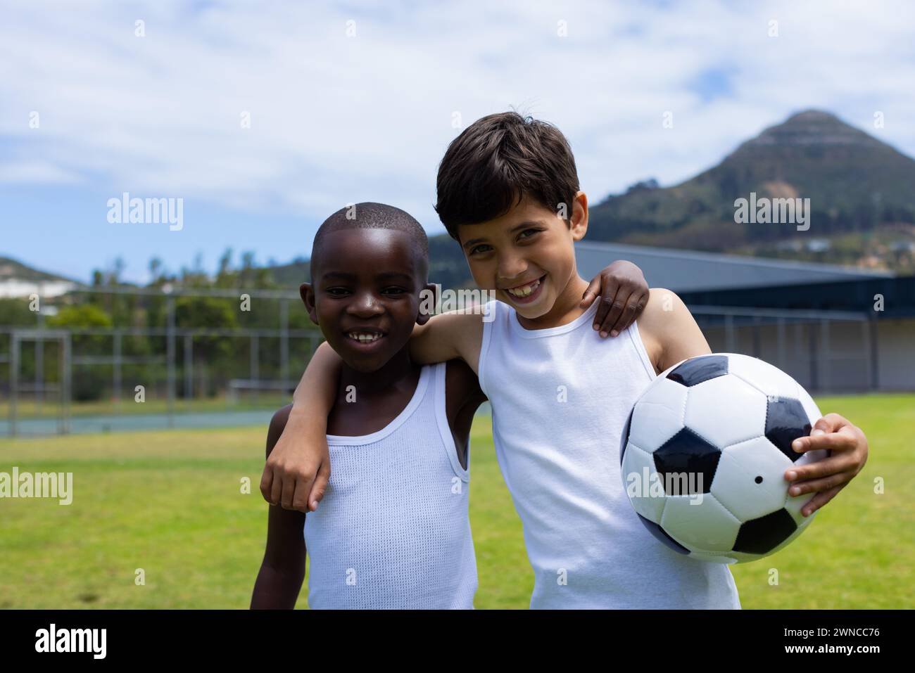 Biracial Boy und afroamerikanischer Boy Smile halten in der Schule einen Fußball Stockfoto