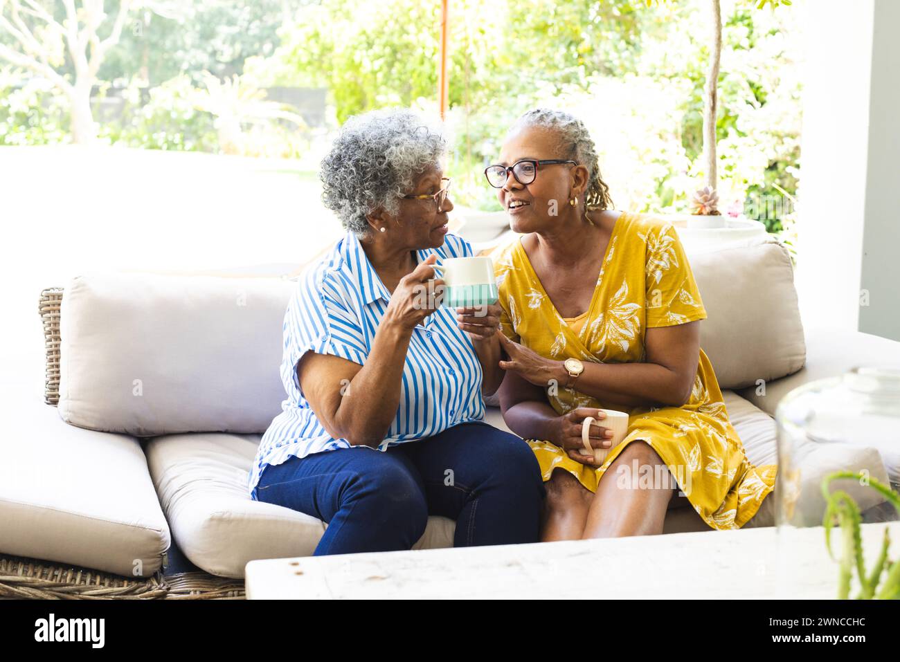 Ältere afroamerikanische Frau und ältere birassische Frau teilen sich einen Moment bei einer Tasse Tee zu Hause Stockfoto