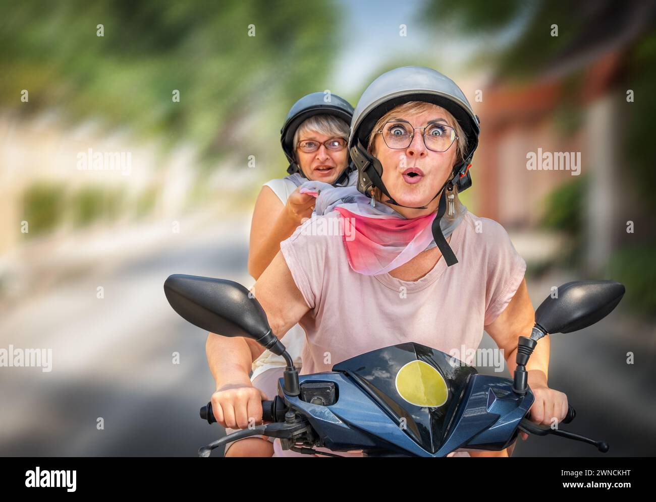 Seniorenfreunde auf dem Moped mit Emotionen auf der Straße Stockfoto