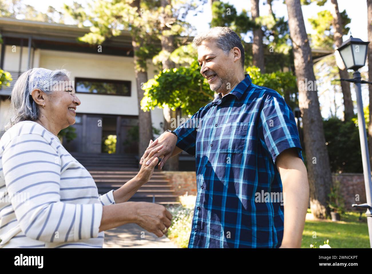 Eine ältere Frau mit weißen Haaren lacht draußen mit einem Mann mit einer Rasse Stockfoto
