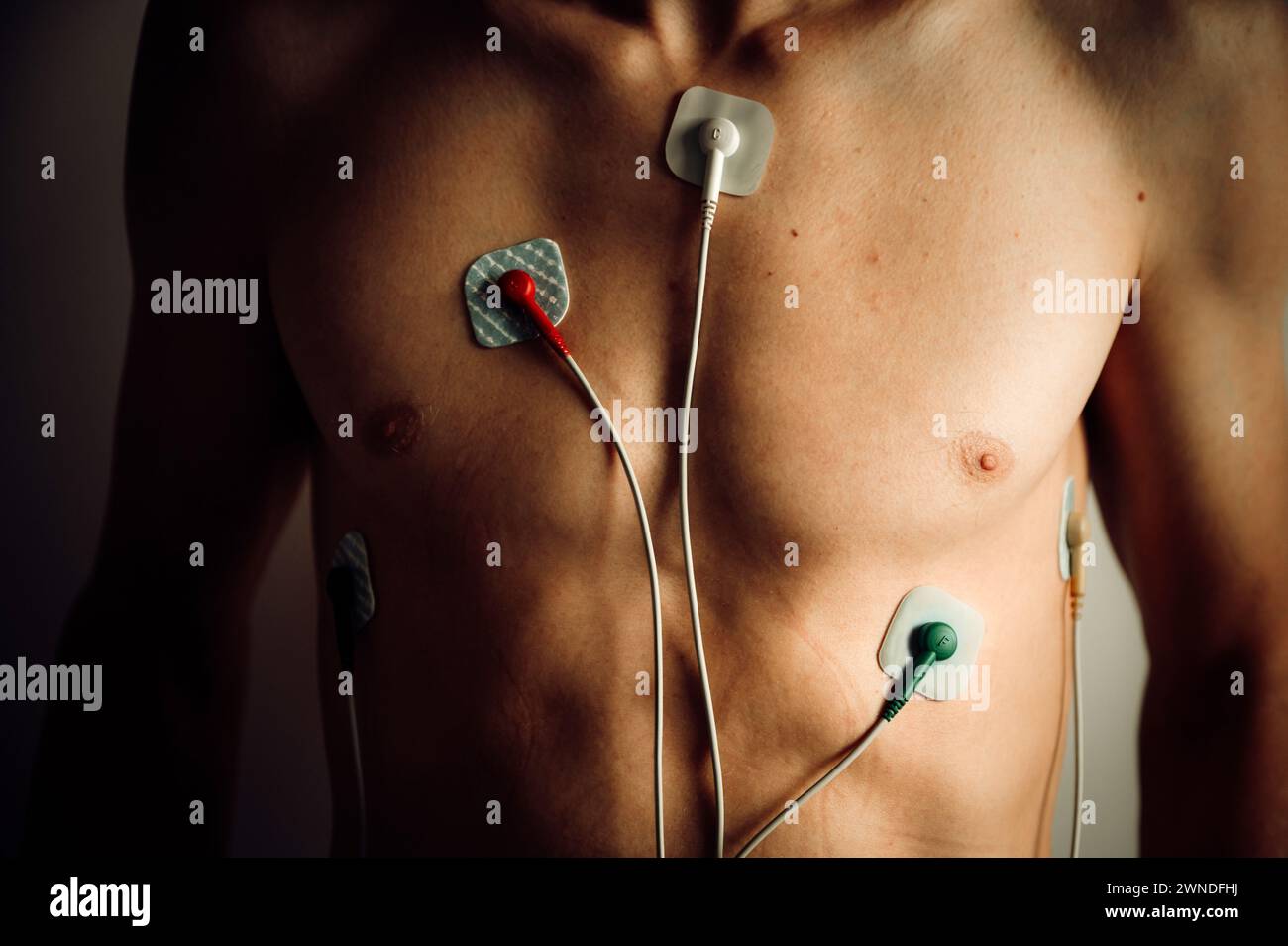 Herzmonitor, EKG, Kardio-Aufzeichnung auf dem Körper eines jungen Mannes. Ein medizinisches Instrument zur Überwachung der Herzfrequenz und der allgemeinen Herzgesundheit. Elektrokarte Stockfoto