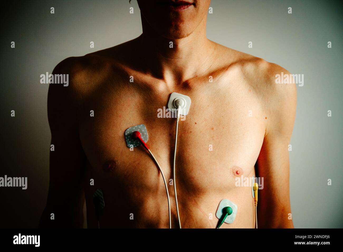 Lebendiges EKG-Display auf der Brust eines jungen Mannes, das den Rhythmus eines gesunden Herzens unter dem Glanz des natürlichen Lichts erfasst. Stockfoto