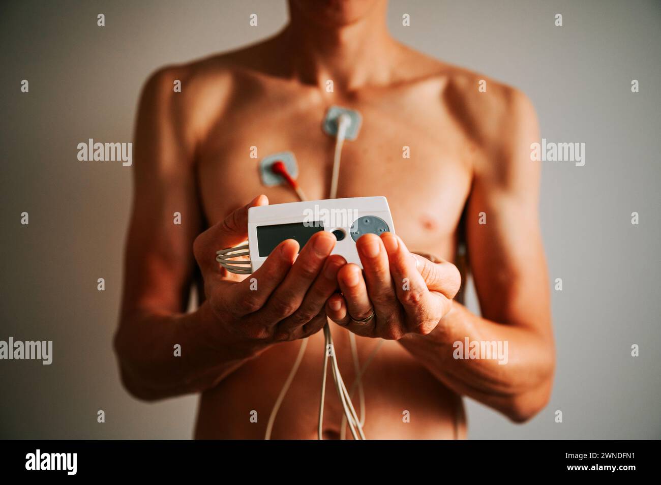 Sinfonie des sonnendurchfluteten Herzens: Der Körper eines jungen Mannes, der mit einem EKG geschmückt ist und den komplizierten Tanz der kardiovaskulären Rhythmen einfängt Stockfoto