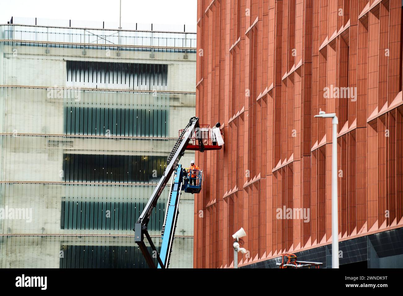 Bauarbeiter auf Hochplattformen, die die Fenster vervollständigen Stockfoto