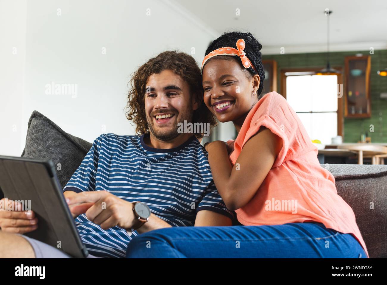 Verschiedene Paare, junge Afroamerikanerin und kaukasischer Mann, teilen sich eine Tafel und lächeln zusammen Stockfoto