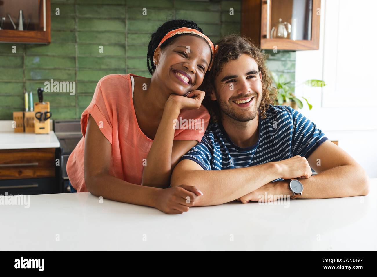 Diverse Paare lächeln herzlich und lehnen sich auf eine Küchenzeile Stockfoto