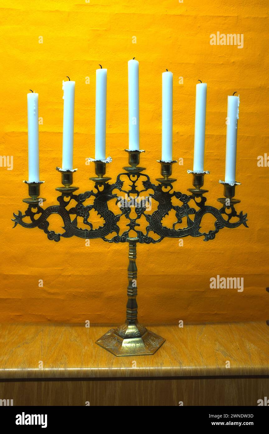 Kerze, Vintage und Halter in der Kirche auf dem Tisch im Inneren des Zimmers oder der Kathedrale. Wachs, Messing und Retro-Kerzenhalter für die Dekoration im Tempel, Holz und Stockfoto