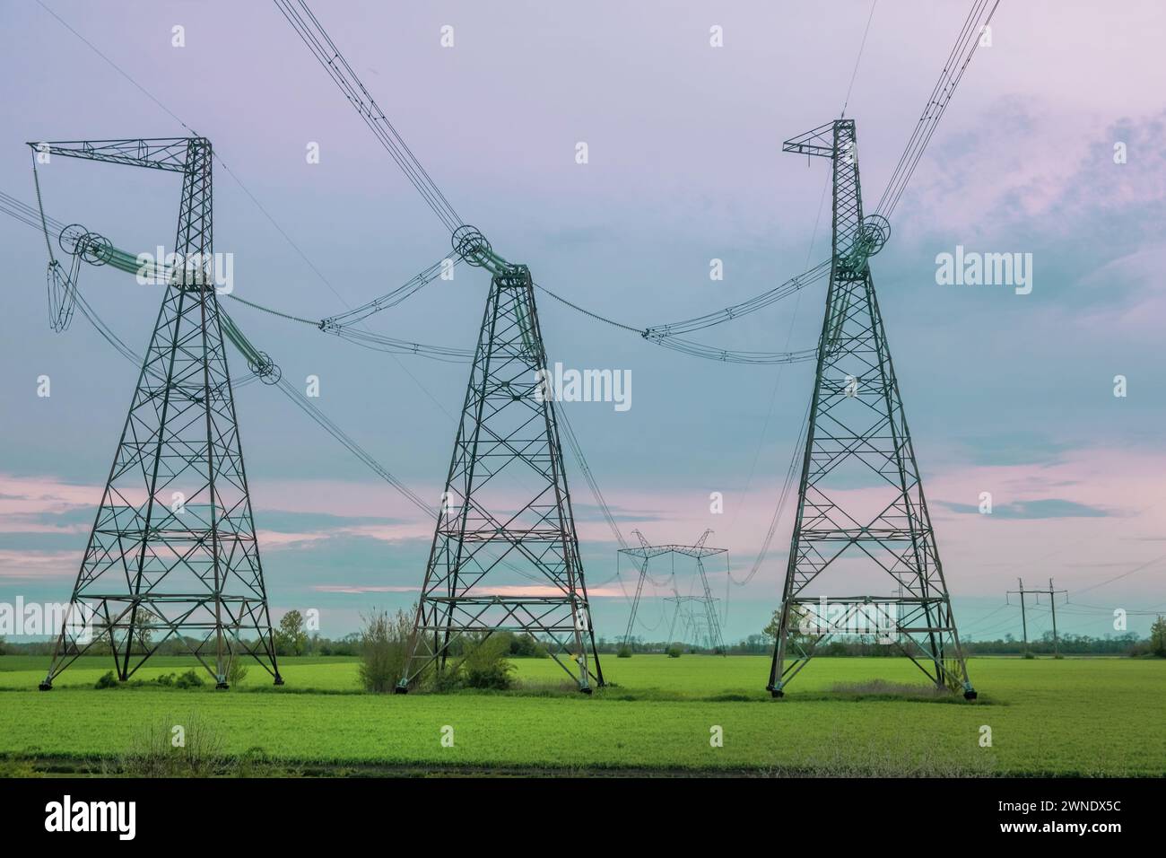 Gruppensilhouette von Sendetürmen, Strommast, Strommast, Stahlgitterturm in der Dämmerung. Struktur Hochspannungssäule, Überkopfleistung Stockfoto